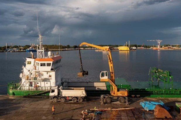 Koparka przeładunkowa i wywrotka na nabrzeżu portowym podczas rozładunku jednostki